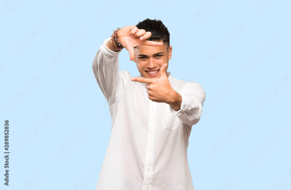 Young man focusing face. Framing symbol on colorful background Young man focusing face. Framing symbol on colorful background
