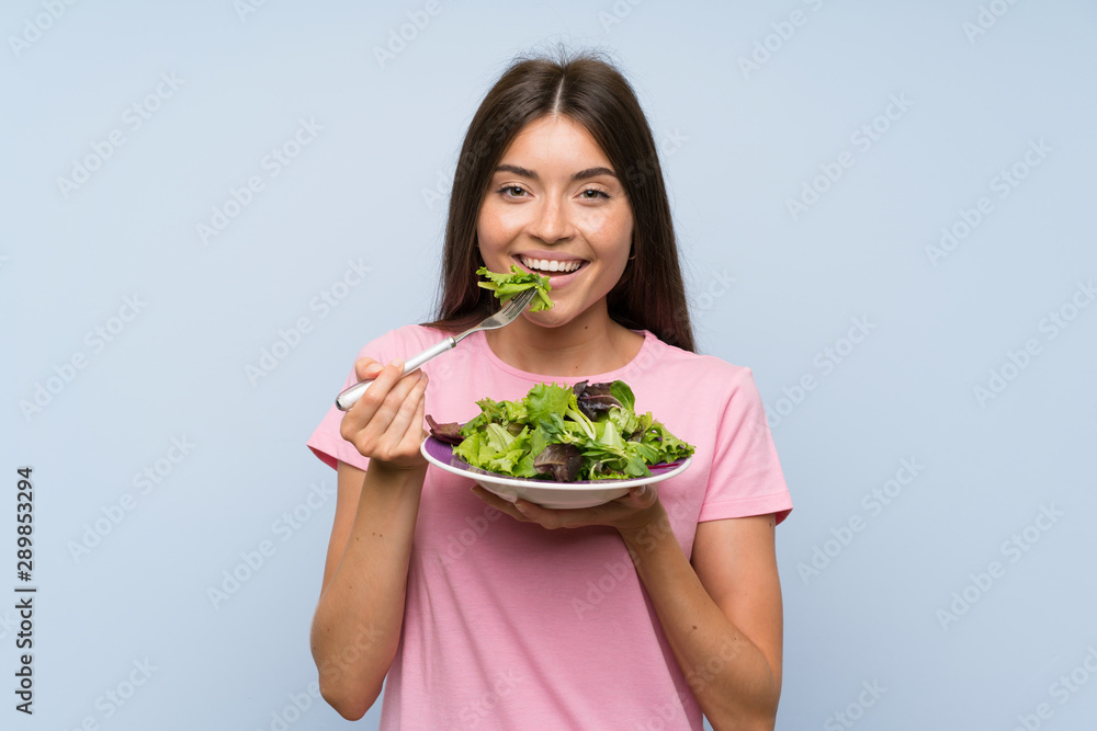 Young woman with salad over isolated blue background Young woman with salad over isolated blue background