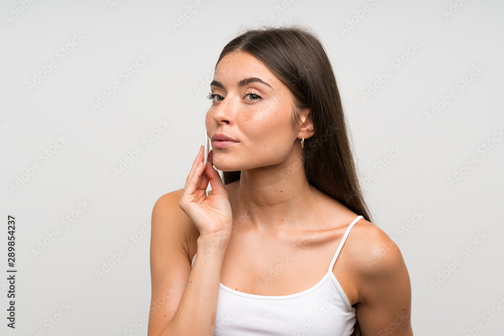 Pretty young woman removing makeup from her face with cotton pad Pretty young woman removing makeup from her face with cotton pad