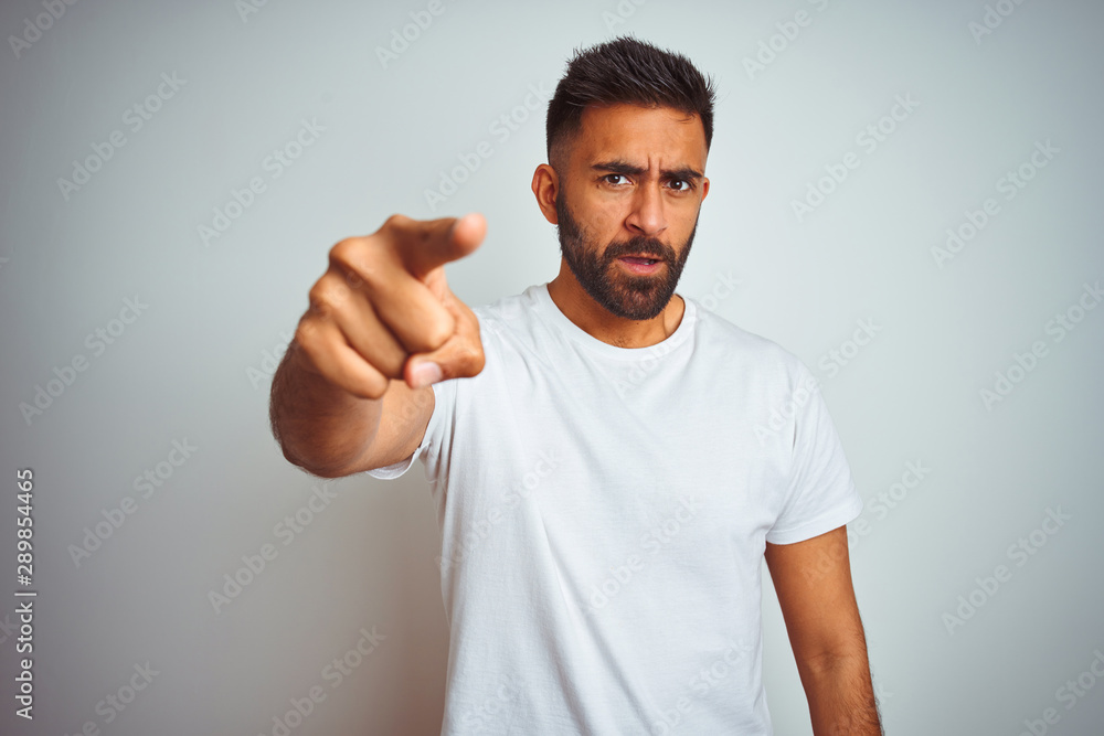 Young indian man wearing t-shirt standing over isolated white background pointing displeased and frustrated to the camera, angry and furious with you Young indian man wearing t-shirt standing over isolated white background pointing displeased and frustrated to the camera, angry and furious with you