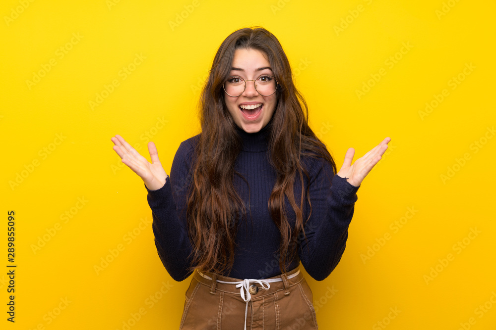 Teenager girl over isolated yellow wall with shocked facial expression Teenager girl over isolated yellow wall with shocked facial expression