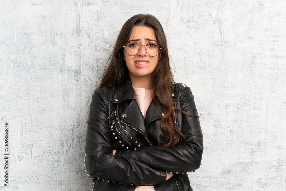 Teenager girl over grunge wall having doubts and with confuse face expression Teenager girl over grunge wall having doubts and with confuse face expression