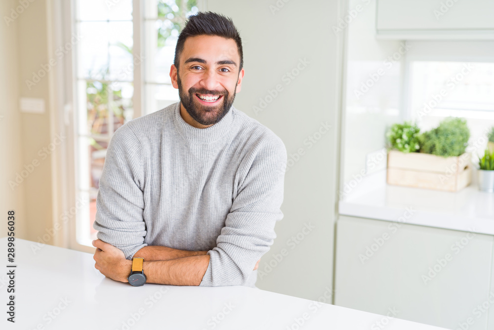 Handsome hispanic man wearing casual sweater at home happy face smiling with crossed arms looking at the camera. Positive person. Handsome hispanic man wearing casual sweater at home happy face smiling with crossed arms looking at the camera. Positive person.