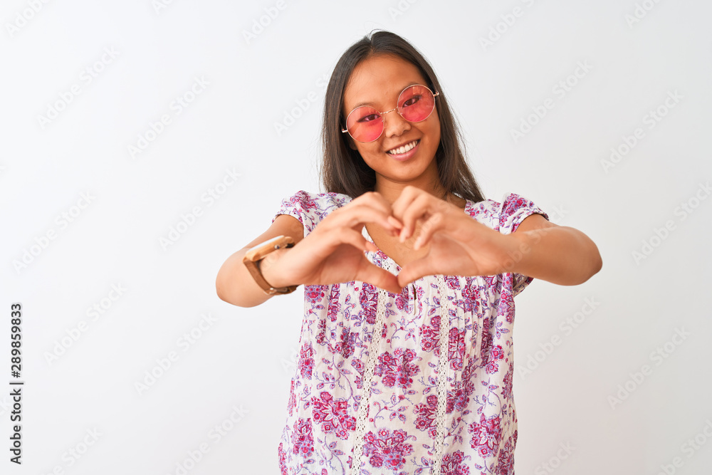 Young chinese woman wearing floral t-shirt and pink glasses over isolated white background smiling in love showing heart symbol and shape with hands. Romantic concept. Young chinese woman wearing floral t-shirt and pink glasses over isolated white background smiling in love showing heart symbol and shape with hands. Romantic concept.