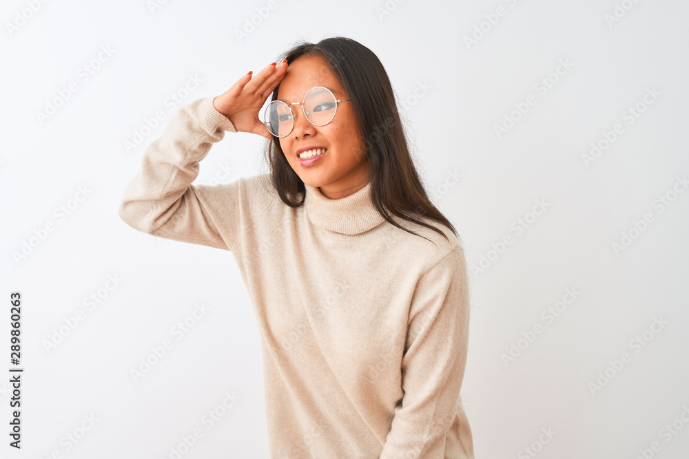Young chinese woman wearing turtleneck sweater and glasses over isolated white background very happy and smiling looking far away with hand over head. Searching concept. Young chinese woman wearing turtleneck sweater and glasses over isolated white background very happy and smiling looking far away with hand over head. Searching concept.