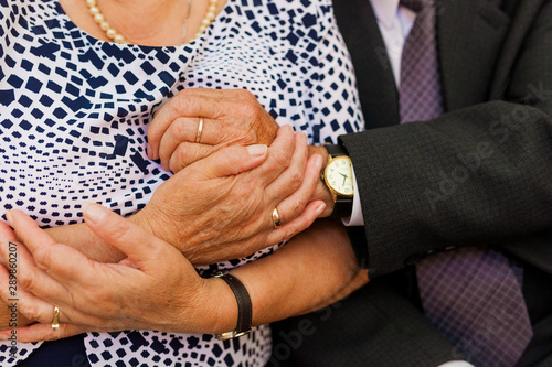 Dłonie pary staruszków, którzy się przytulają, dłonie z obrączkami na palcach, gest miłości photo