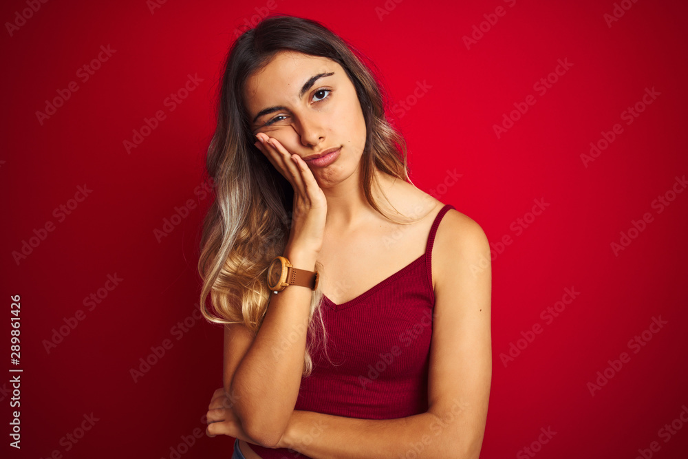 Young beautiful woman wearing a t-shirt over red isolated background thinking looking tired and bored with depression problems with crossed arms. Young beautiful woman wearing a t-shirt over red isolated background thinking looking tired and bored with depression problems with crossed arms.