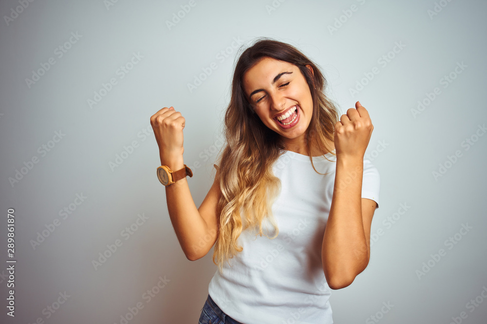 Young beautiful woman wearing casual white t-shirt over isolated background celebrating surprised and amazed for success with arms raised and eyes closed. Winner concept.