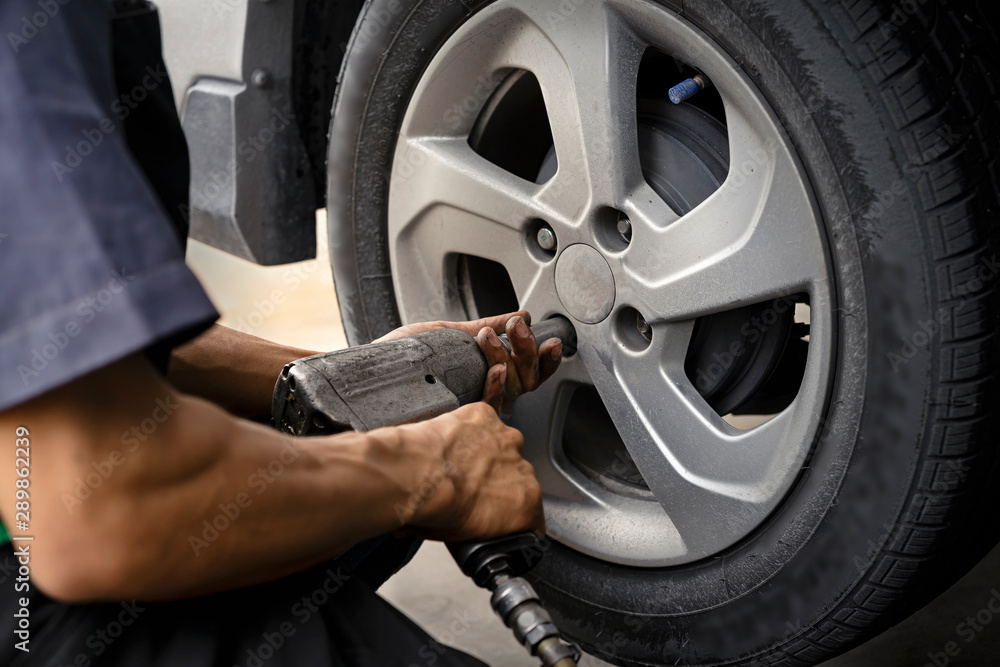 Man using car mechanic Block the wind wheel. To check your tires and brake for car.Auto mechanic Preparing For the work. Man using car mechanic Block the wind wheel. To check your tires and brake for car.Auto mechanic Preparing For the work.