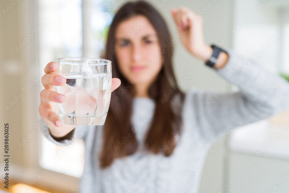 Beautiful young woman drinking a fresh glass of water annoyed and frustrated shouting with anger, crazy and yelling with raised hand, anger concept Beautiful young woman drinking a fresh glass of water annoyed and frustrated shouting with anger, crazy and yelling with raised hand, anger concept
