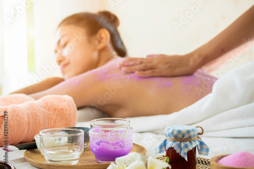 Spa therapist scrub salt on young woman back and body at spa salon