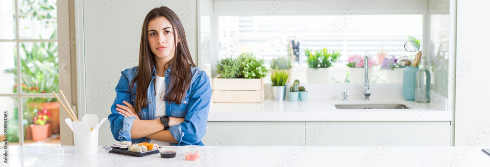 Wide angle picture of beautiful young woman eating delivery sushi skeptic and nervous, disapproving expression on face with crossed arms. Negative person. Wide angle picture of beautiful young woman eating delivery sushi skeptic and nervous, disapproving expression on face with crossed arms. Negative person.