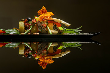 Black sesame tuna with potato, greens and candied tomatoes. Exquisite dish. Creative restaurant meal concept. Haute couture food on black with reflection. Fine dining concept.