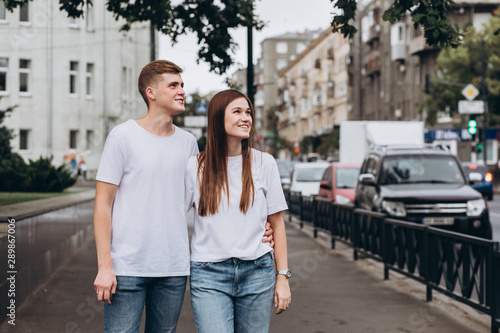 young couple walks the streets of the city and hold hands. guy and girl in white t-shirts and jeans outdoors. Teenagers walk in the autumn city. Happy young couple. © Stanislav