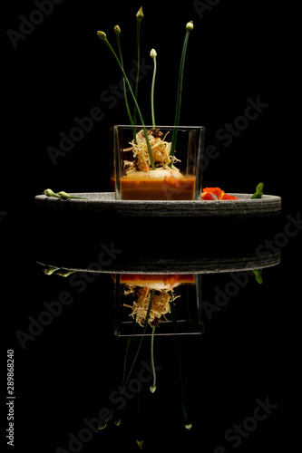 Prawn ballotine on lobster bisque. Exquisite dish. Creative restaurant meal concept. Haute couture food on black with reflection. Fine dining concept. photo