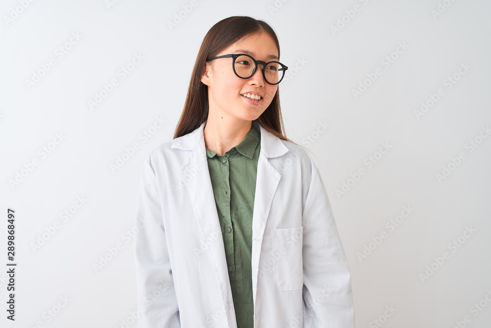 Young chinese scientist woman wearing coat and glasses over isolated white background looking away to side with smile on face, natural expression. Laughing confident. Young chinese scientist woman wearing coat and glasses over isolated white background looking away to side with smile on face, natural expression. Laughing confident.