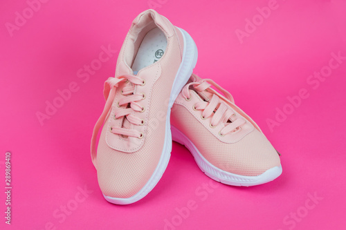 Women's sports shoes. Sneakers for running. Stylish trendy pink fabric sneakers. Women's sports shoes on a pink background.