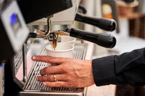 Barista making espresso drinks to paper cups