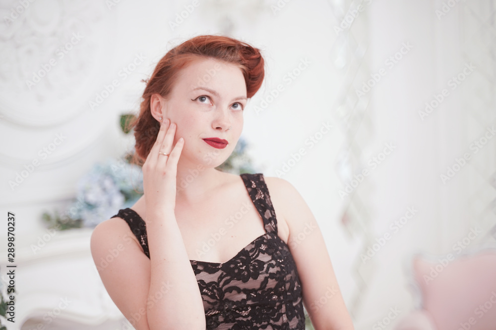 classic young beautiful woman posing in elegant evening dress indoors in her apartment alone