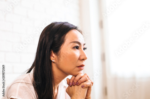 Mature Asian woman putting two hands together and praying at home. Joined and Clasped Hands. Spirituality and Religion concept