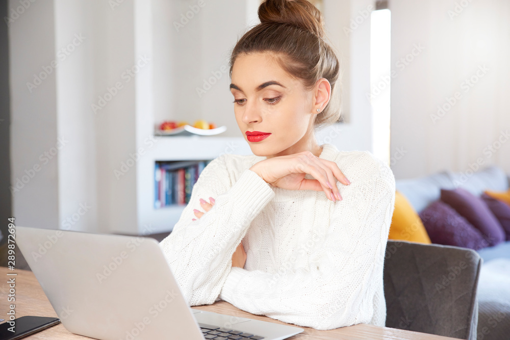 Smiling young attractive woman with laptop sitting at home and studying Smiling young attractive woman with laptop sitting at home and studying