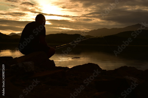 silhouette of man on top of mountain at sunset