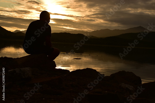 silhouette of man on top of mountain at sunset