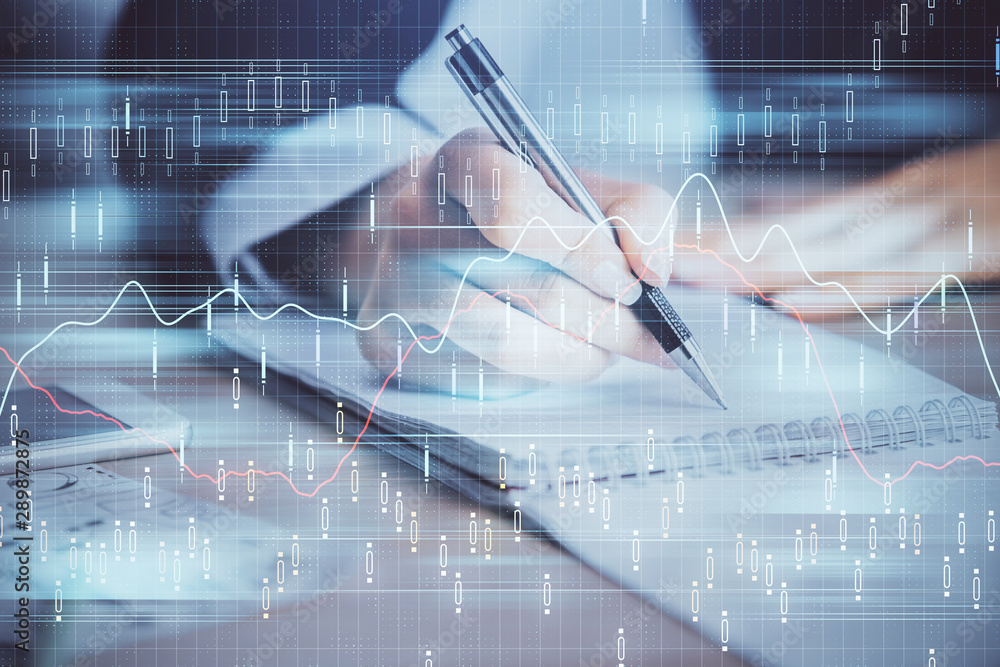 A woman hands writing information about stock market in notepad. Forex chart holograms in front. Concept of research. Multi exposure A woman hands writing information about stock market in notepad. Forex chart holograms in front. Concept of research. Multi exposure