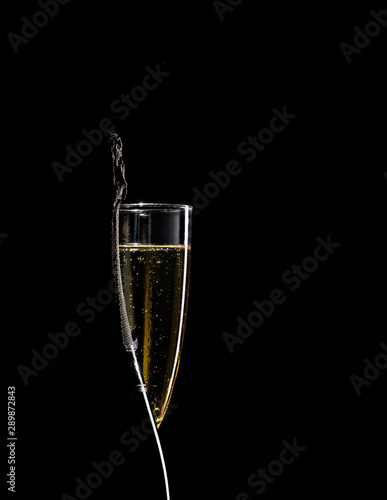 Bottler of champagne in front of glass isolated on a black background photo