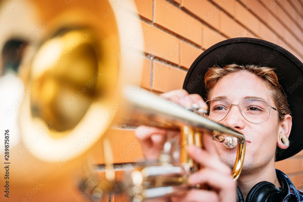 Obraz premium Young man with piercings playing trumpet.