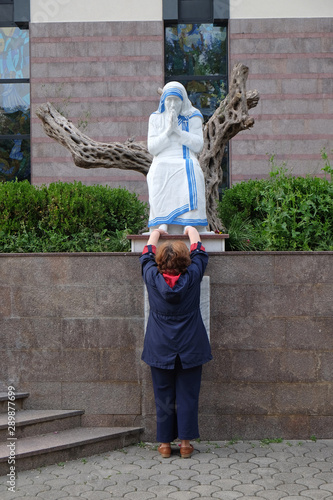 A woman prays in front of the statue of St. Mother Teresa in front of St. Paul's Cathedral in Tirana, Albania photo