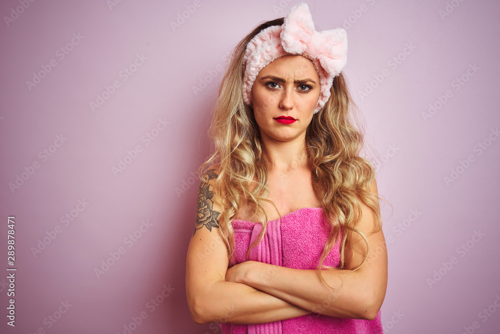 Young beautiful woman wearing towel after shower over pink isolated background skeptic and nervous, disapproving expression on face with crossed arms. Negative person. Young beautiful woman wearing towel after shower over pink isolated background skeptic and nervous, disapproving expression on face with crossed arms. Negative person.