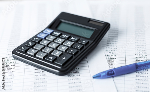 Calculator with pen on white paper with numbers. Business and Finance accounting concept.