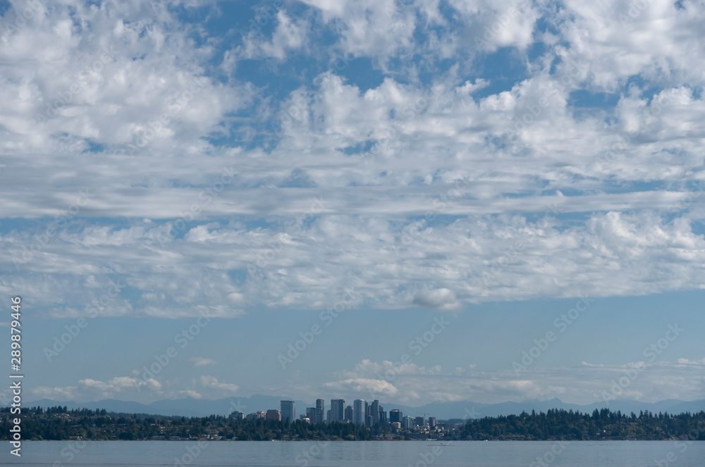 Lake Washington with the Bellevue skyline in the distance under large partly cloudy sky.