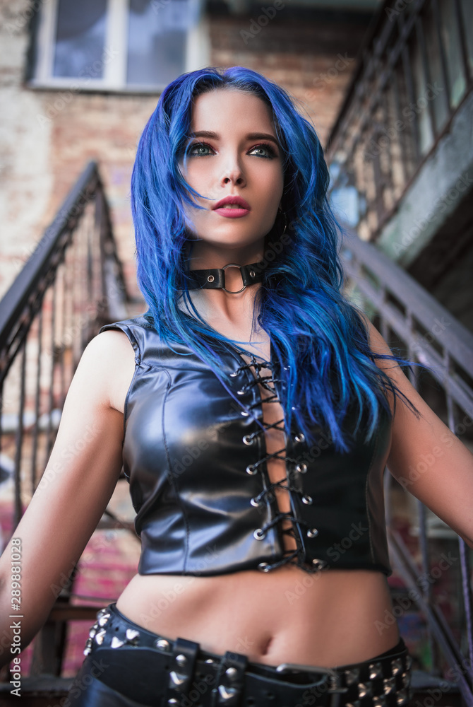 Cute sexy rock girl with blue hair (informal model), dressed in black  leather pants and topic, stands on staircase Stock Photo | Adobe Stock