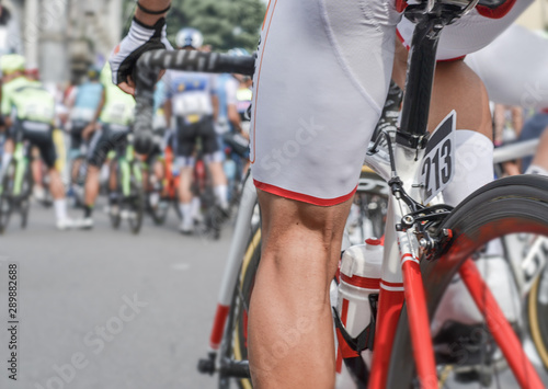 close up of a leg of professional cyclist sat on his bicycle, just before start a race. bottom up view.