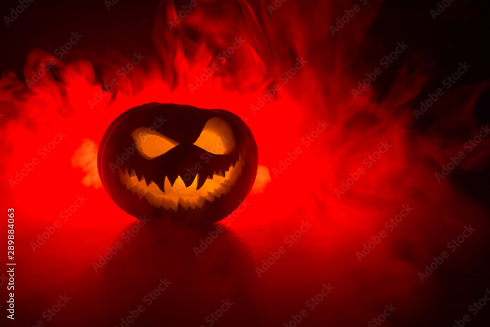 Fototapeta premium Halloweenowy uśmiech dyni i przerażające oczy na imprezową noc. Zamknij widok strasznej dyni Halloween z oczami świecącymi wewnątrz na czarnym tle