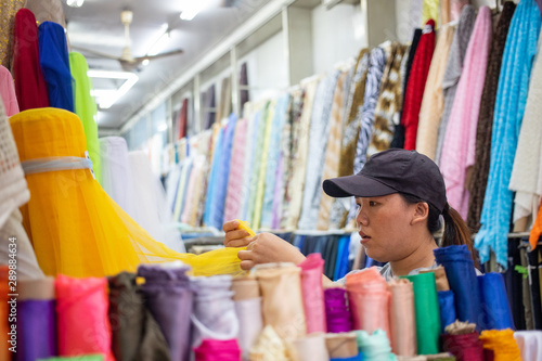 Photography Asian woman selecting many kinds of cloth in fabric shop