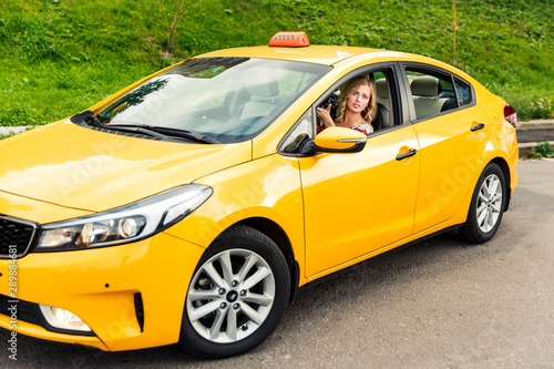 Photo of woman driver sitting in yellow taxi on summer.