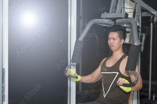 Strong muscular asian man lifting weights exercise his breast in fitness gymnasium,sport and healthy concept.