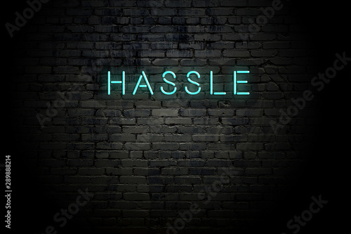 Highlighted brick wall with neon inscription hassle