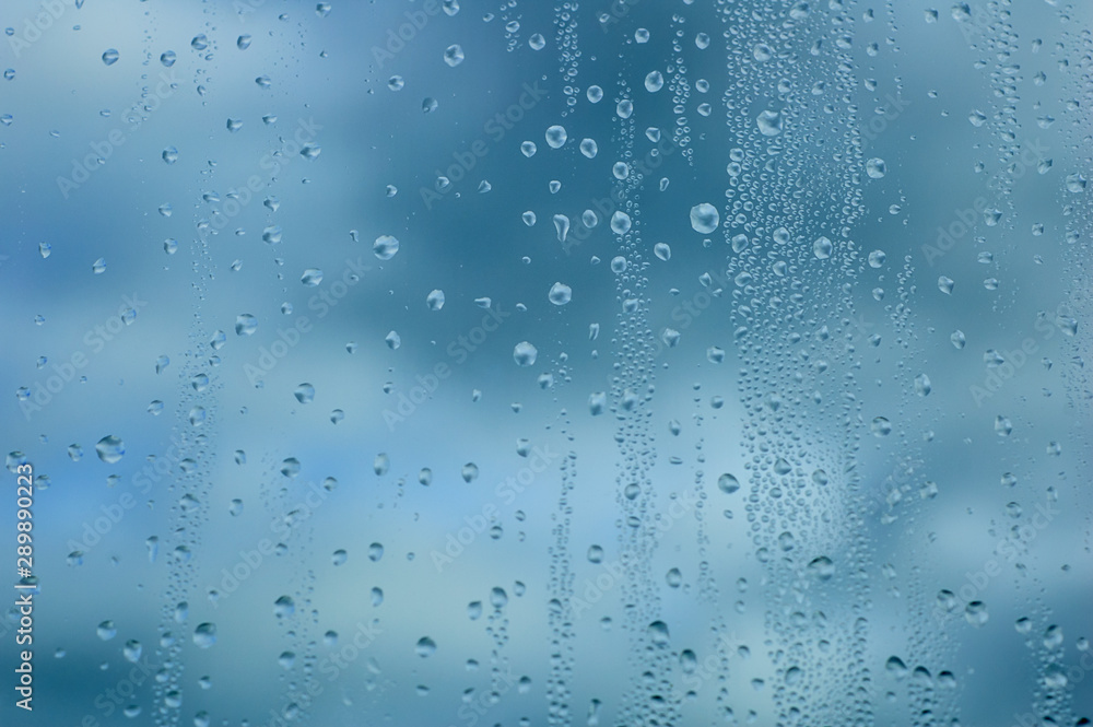 Drops of water on glass against the background of the sky of dark thunderclouds. Close-up. Drops of water on glass against the background of the sky of dark thunderclouds. Close-up.