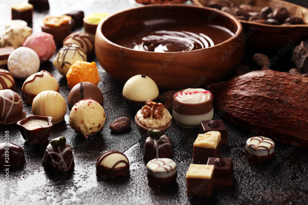 a lot of variety chocolate pralines, belgian confectionery gourmet chocolate on rustic dark background