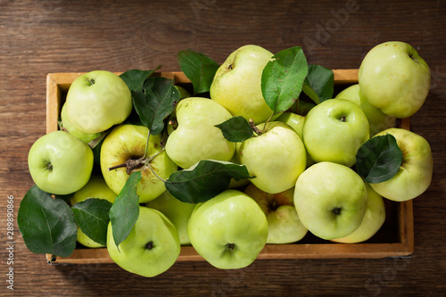 fresh green apples with leaves in a wooden box
