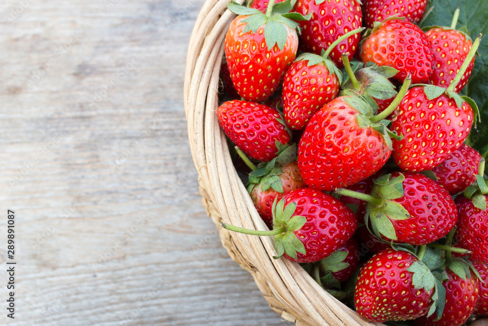 Closeup fresh strawberry in bamboo basket. Over wood table. Top view with copy space.