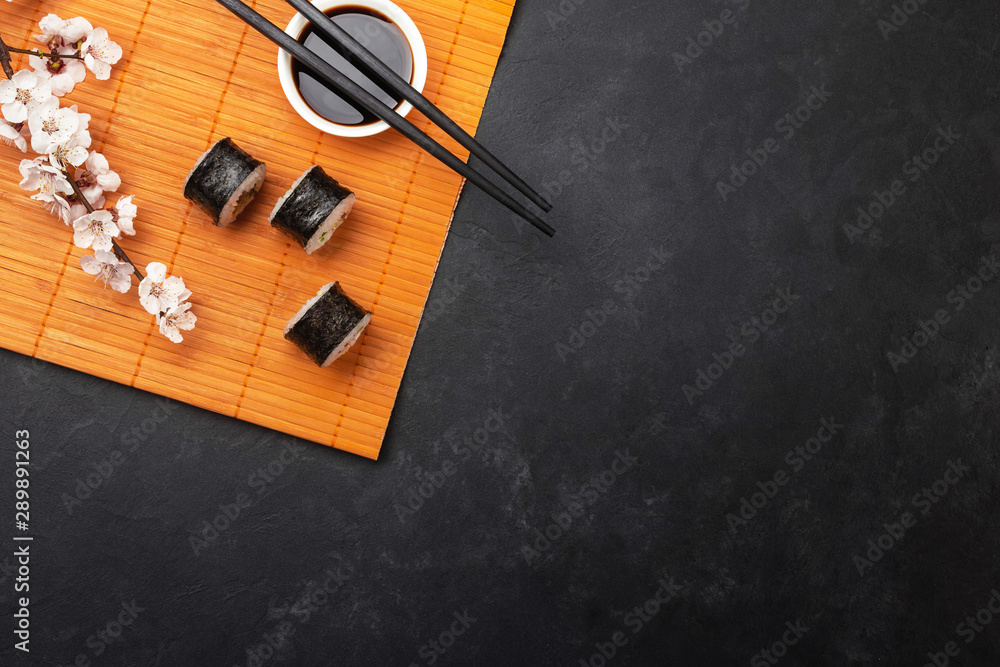 Φωτογραφία Set of sushi and maki rolls with branch of white flowers on stone table