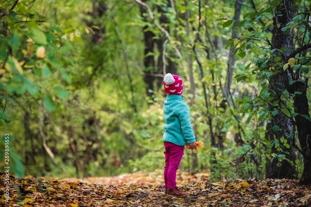 Rear view child looking forward standing alone in forest Rear view child looking forward standing alone in forest