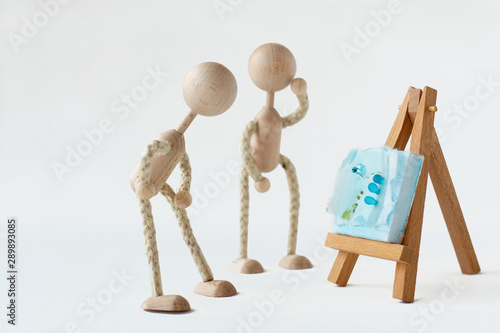 Two figurines standing in front of a piece of art on an easel