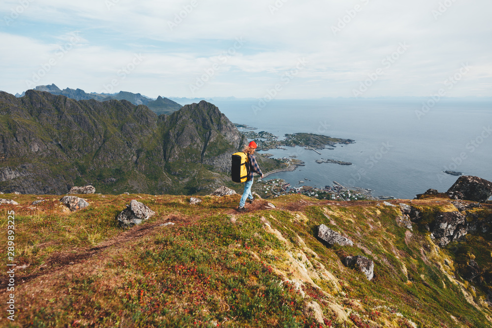 Alone professional traveler with backpack on high mountain standing on the edge cliff rock and looking away. Adventure lifestyle vacation