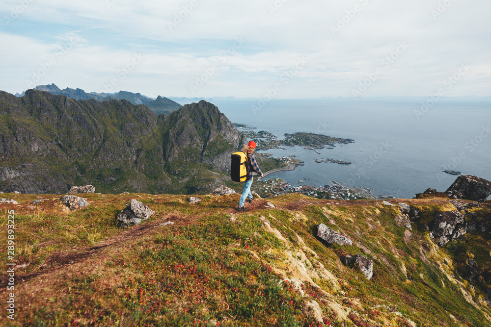 Alone professional traveler with backpack on high mountain standing on the edge cliff rock and looking away. Adventure lifestyle vacation Alone professional traveler with backpack on high mountain standing on the edge cliff rock and looking away. Adventure lifestyle vacation